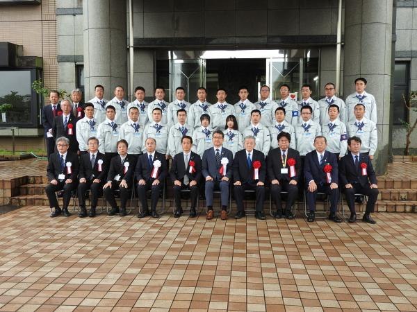 宮崎県産業開発青年隊への入隊記念の集合写真。作業服の隊員と当社の社員が並んでいる