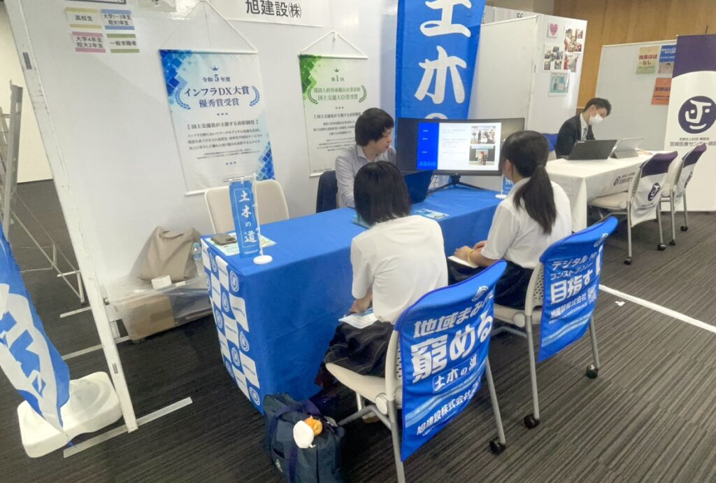 旭建設ブースで学生に会社説明を行う社員