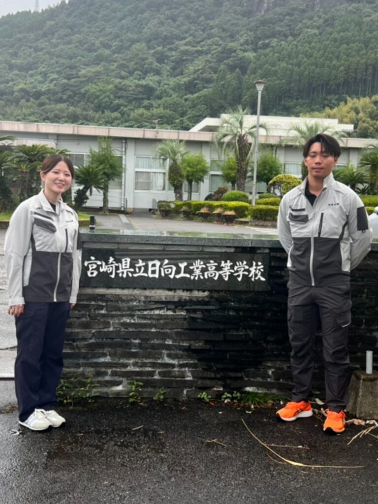 宮崎県立日向工業高等学校の銘板の前で、参加した当社の社員