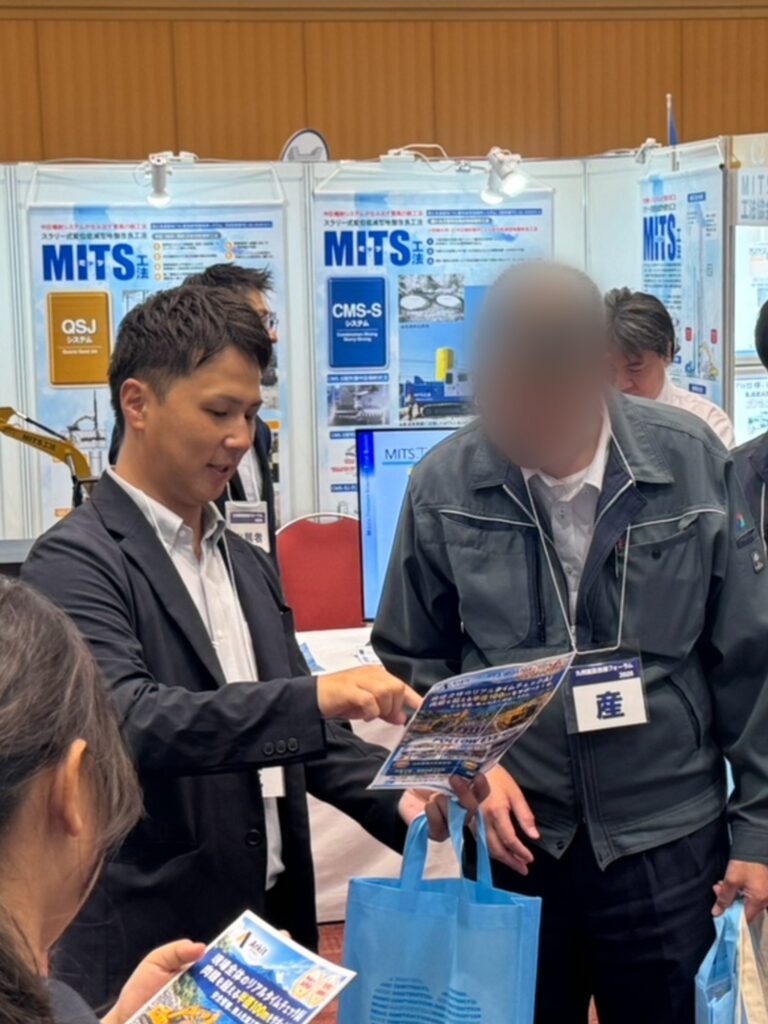 FOLLOW EYE のチラシを見せて説明する社員