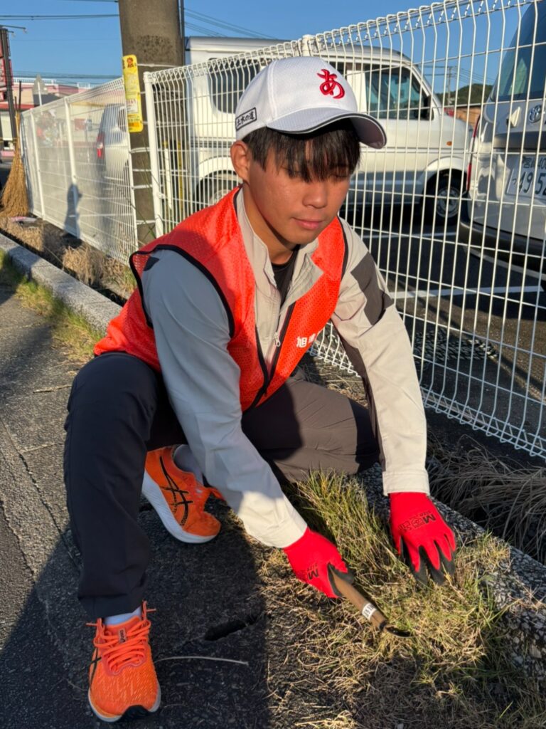縁石沿いの草を刈り取る社員
