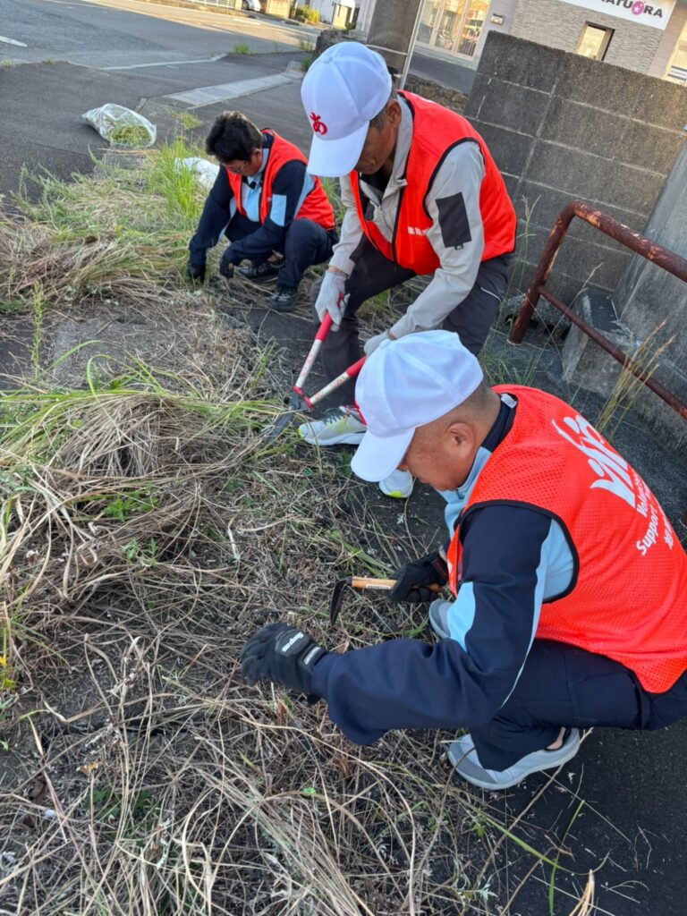 剪定ばさみと鎌で草を刈る社員